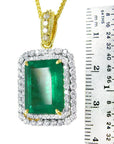 This yellow gold emerald pendant is next to a ruler for scale on a white background