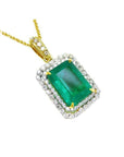 A yellow gold emerald pendant displaying the topside rectangular emerald surrounded by a double halo diamond.
