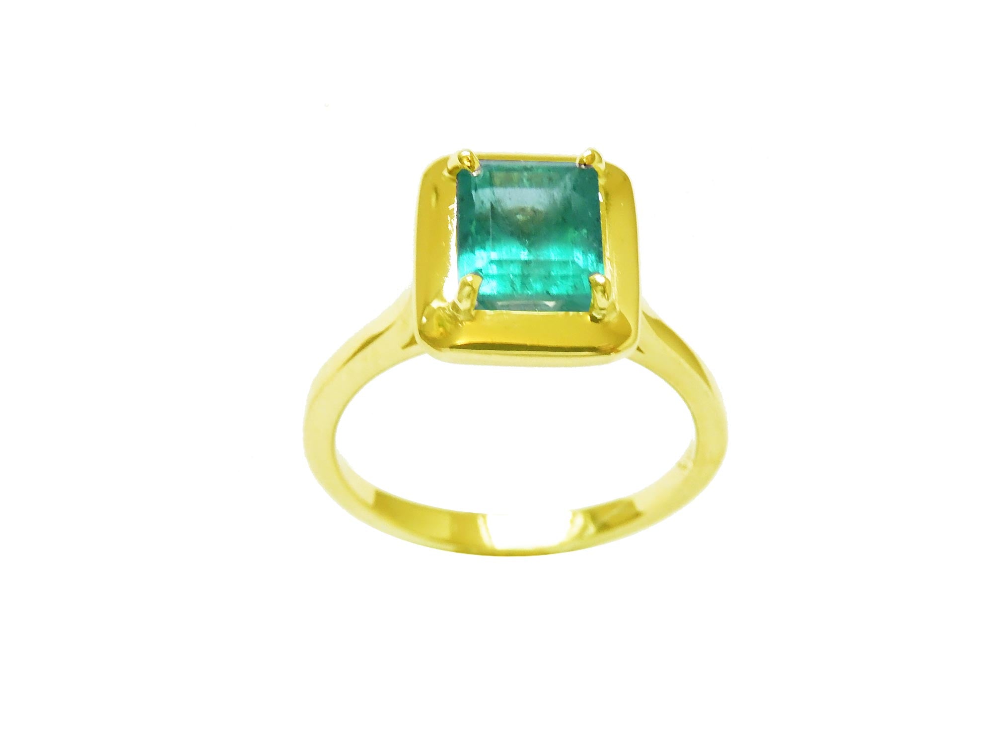 A yellow gold emerald solitaire ring displaying a rectangular emerald into a wide bezel and prong set.