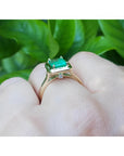 1.22 carat emerald-cut Muzo Colombian emerald solitaire ring in 14K yellow gold with a small diamond accent.