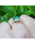 1.22 carat emerald-cut Muzo Colombian emerald solitaire ring in 14K yellow gold with a small diamond accent.