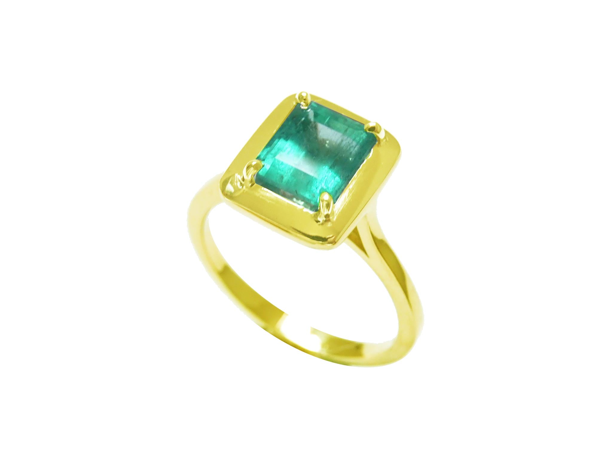 The tilted position of this emerald solitaire ring shows the top gemstone encased in wide bezels and shank profile.