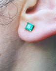 Close-up of an ear with a emerald stud earring.