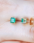 Push backs emerald stud earrings on a hand.