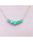14K gold necklace with five round, medium green Colombian emeralds in elegant basket settings.