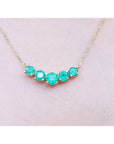 14K gold necklace with five round, medium green Colombian emeralds in elegant basket settings.