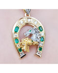 18K yellow gold horseshoe pendant with emeralds, diamonds, and two horse heads.