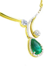 Close view of a gold necklace with a green teardrop emerald pendant halo diamond on a white background