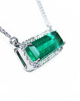 zoom-in view of a 18k white gold elongated emerald necklace east west orientation halo diamonds