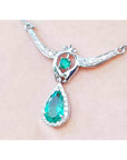 Zoom-in view of a white gold necklace with natural emerald teardrop pendant on a woman's collar
