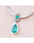 Pear shaped emerald necklace with diamond halo and round emerald accent in 14K white gold.