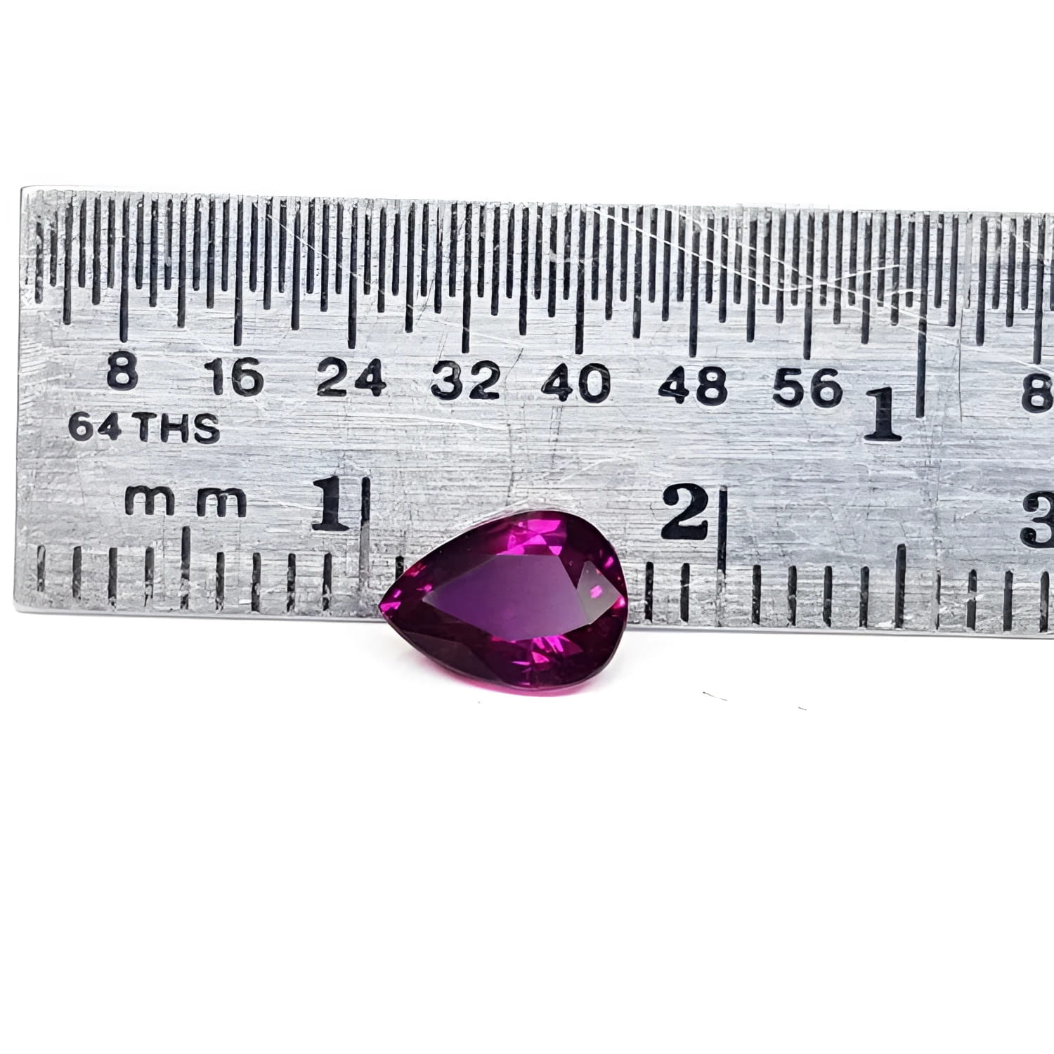 1.00-carat natural pear-shaped ruby gemstone, deep red, next to a ruler for scale.