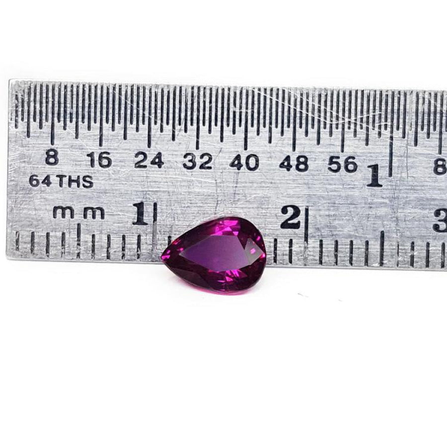 1.00-carat natural pear-shaped ruby gemstone, deep red, next to a ruler for scale.
