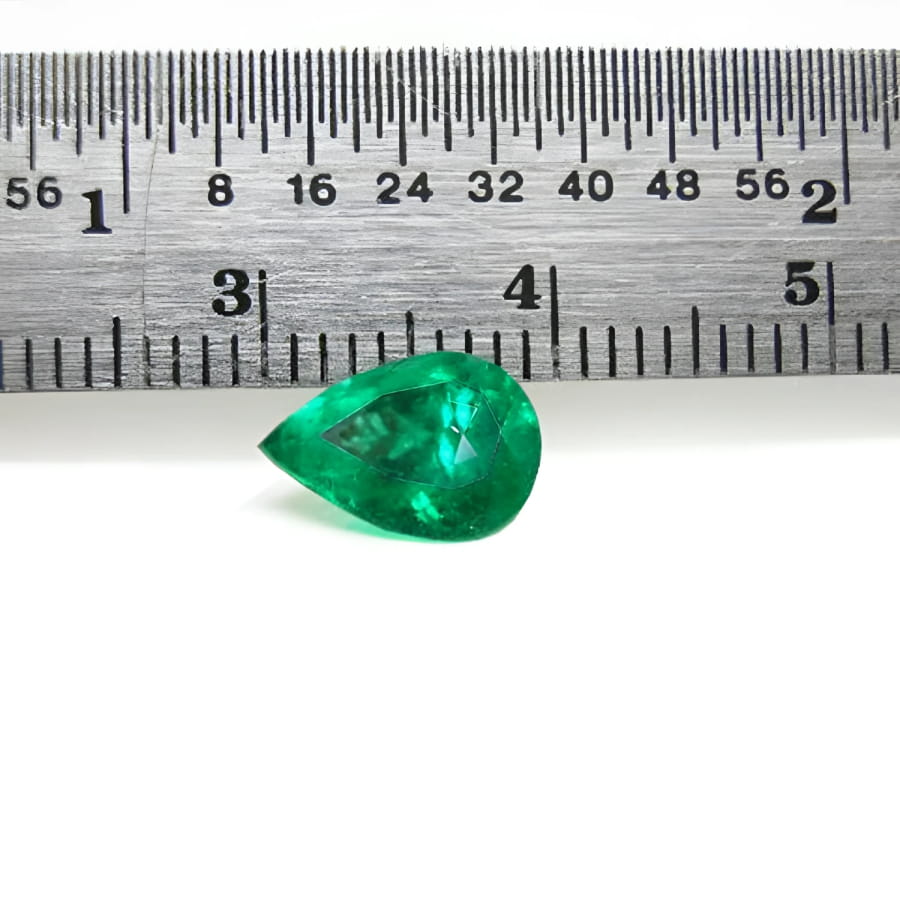 1.44 carat natural pear-cut Colombian emerald with a vibrant medium-deep green hue, shown next to a ruler.
