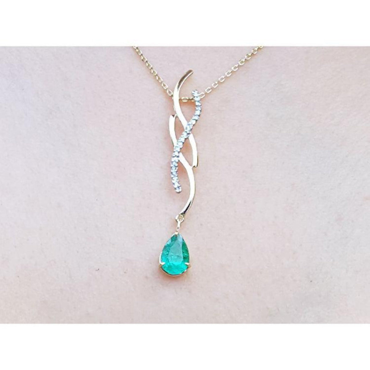 14K yellow gold twisted slider necklace with a pear-shaped emerald and diamond accents.