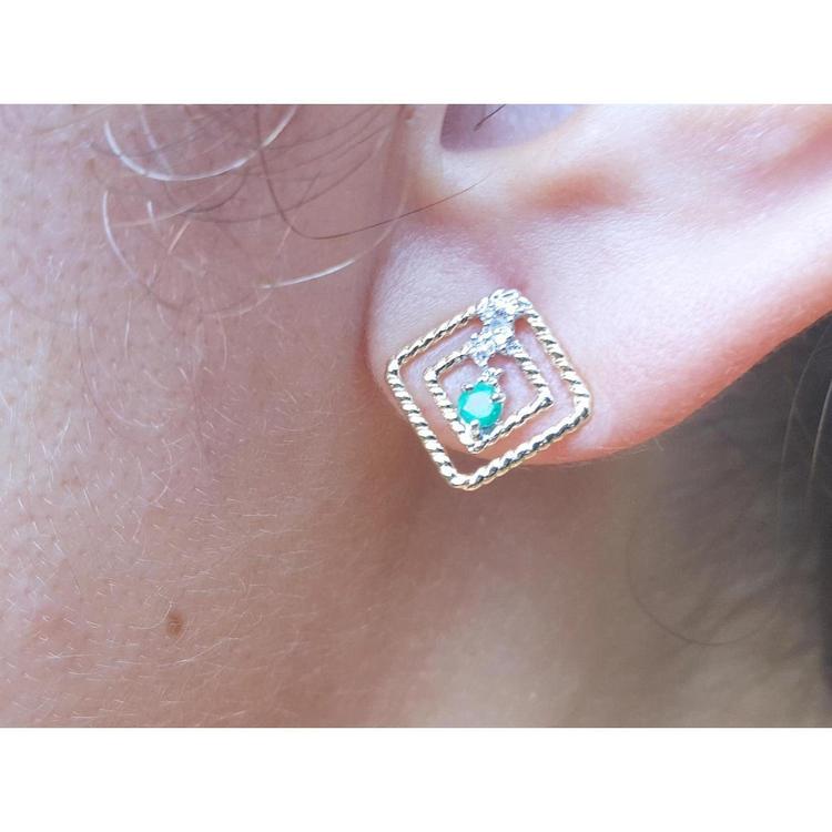 close-up of an emerald earring with double rope frame on an earlobe.
