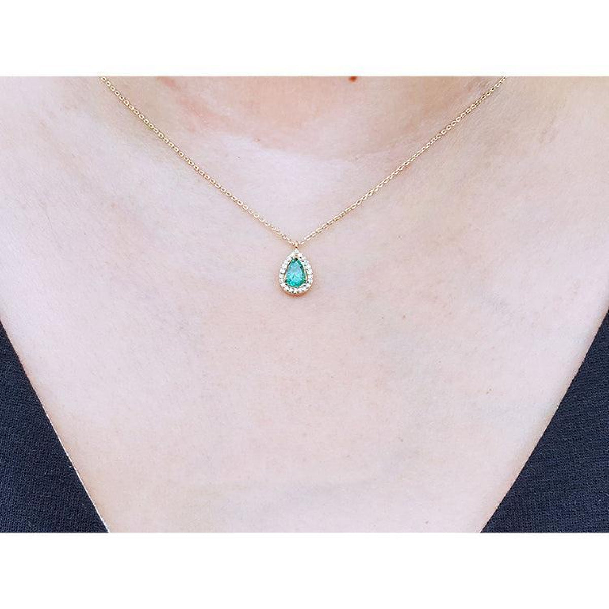 Pear-shaped natural emerald necklace with diamond halo on 14K yellow gold chain.