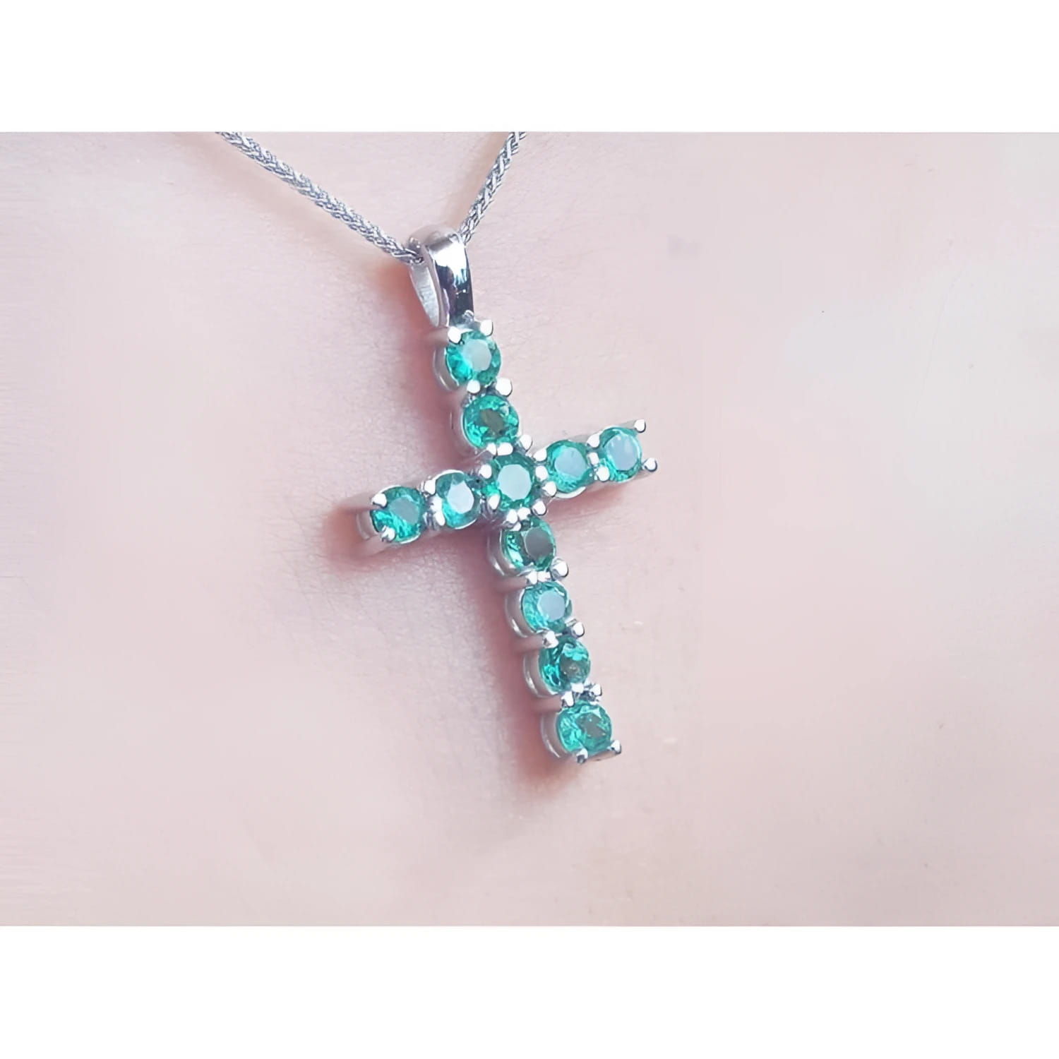 18K white gold cross pendant necklace with eleven round-cut natural Colombian emeralds.