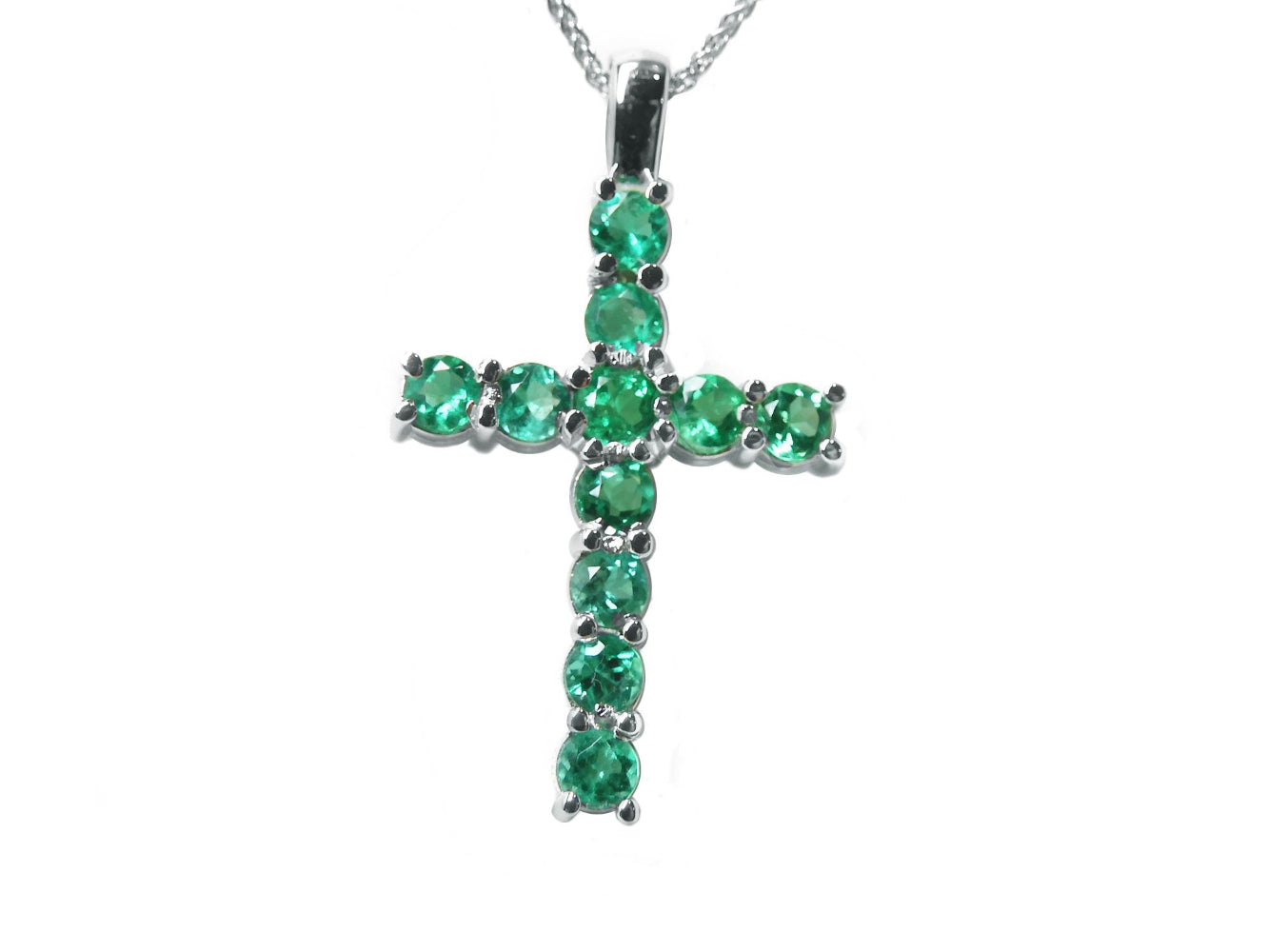 Cross-shaped pendant with natural colombian emeralds on a toside position display.