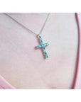 18K white gold cross pendant with eleven round-cut Colombian emeralds on a delicate chain.