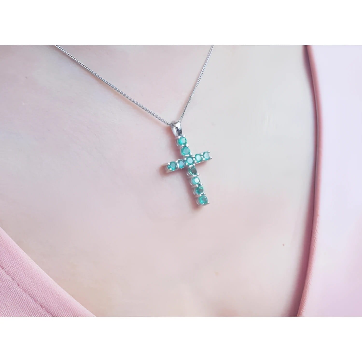 18K white gold cross pendant with eleven round-cut Colombian emeralds on a delicate chain.