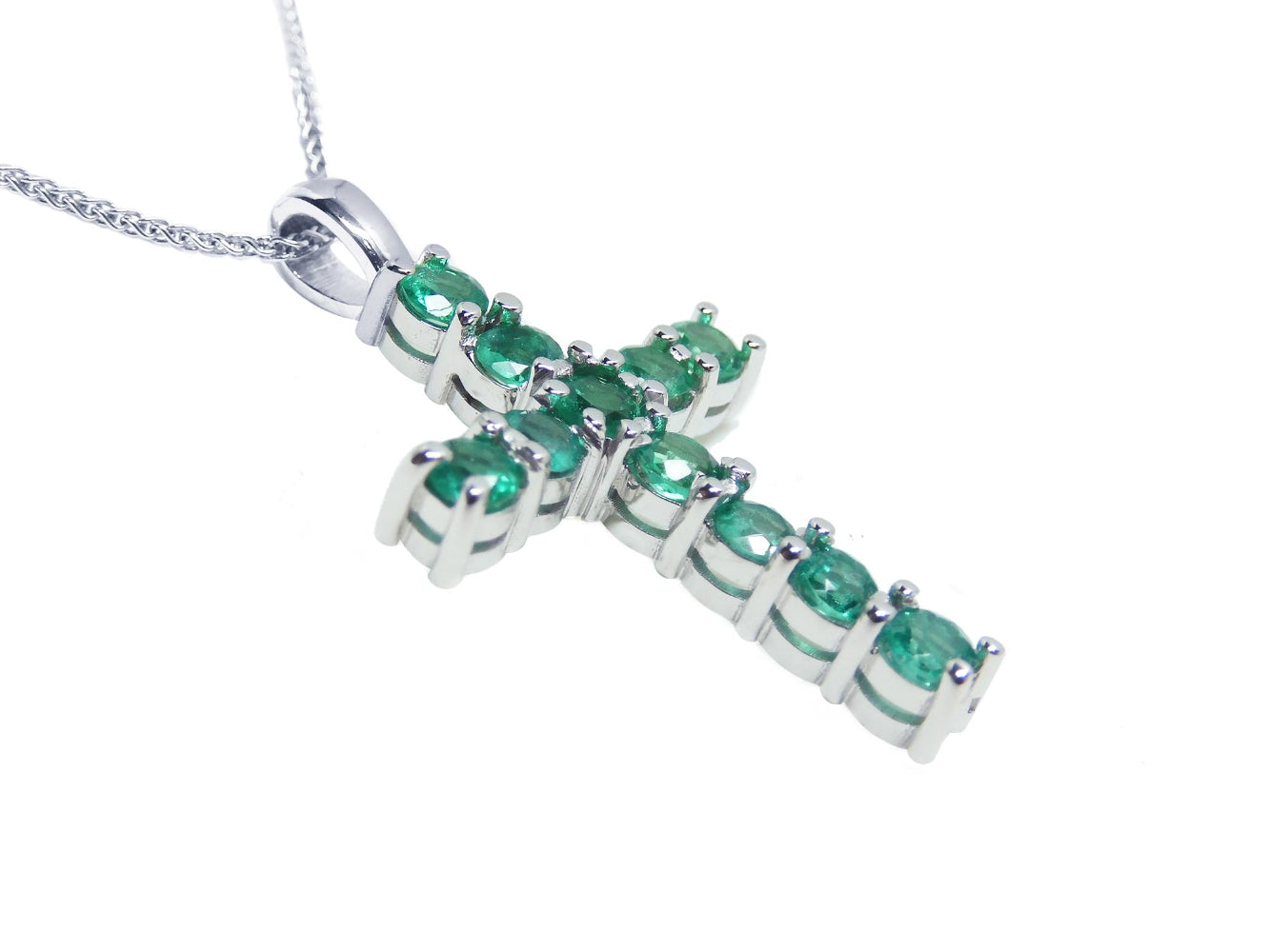 18k white gold cross pendant with natural colombian emeralds on a side profile position view.