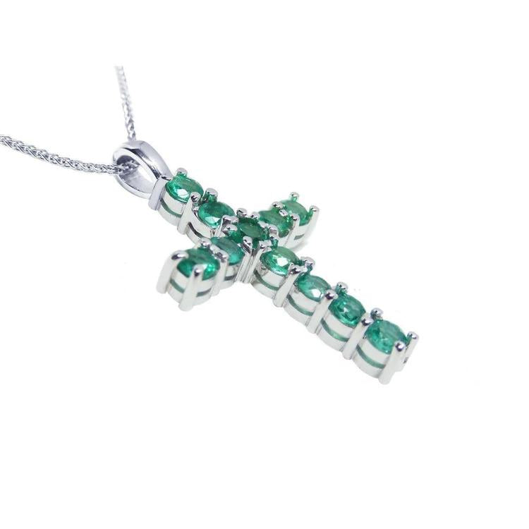 18k white gold cross pendant with natural colombian emeralds on a side profile position view.