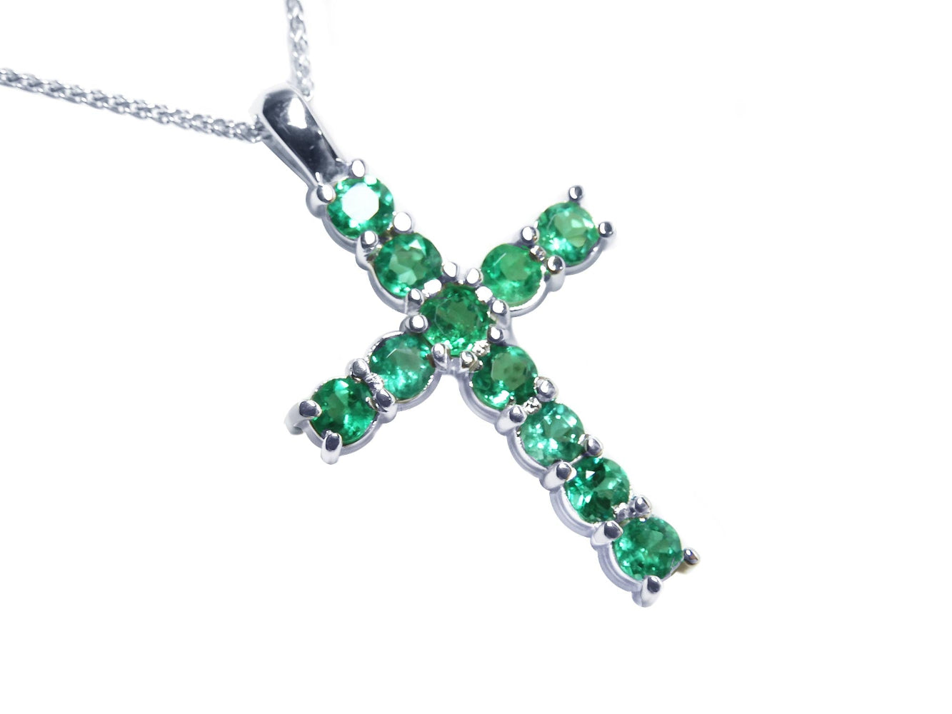 A 18k white gold emerald cross pendant necklace on a toside position view.