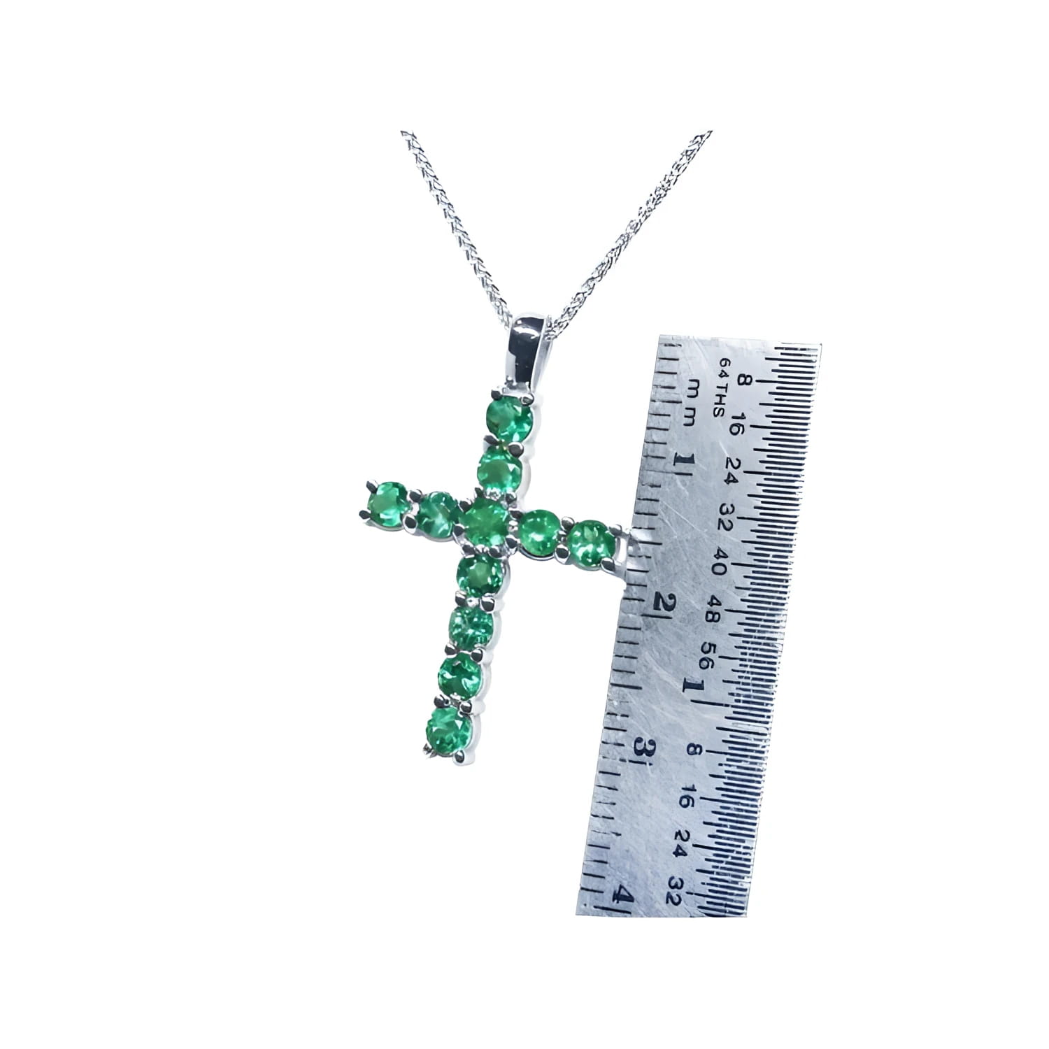 18K white gold cross pendant necklace with eleven round-cut Colombian emeralds, shown next to a ruler.