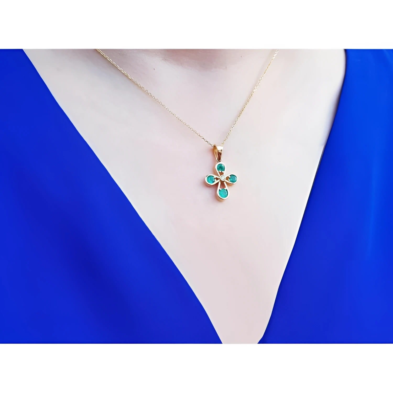 Emerald cross pendant with round-cut emeralds and a diamond accent, crafted in 18K yellow gold.