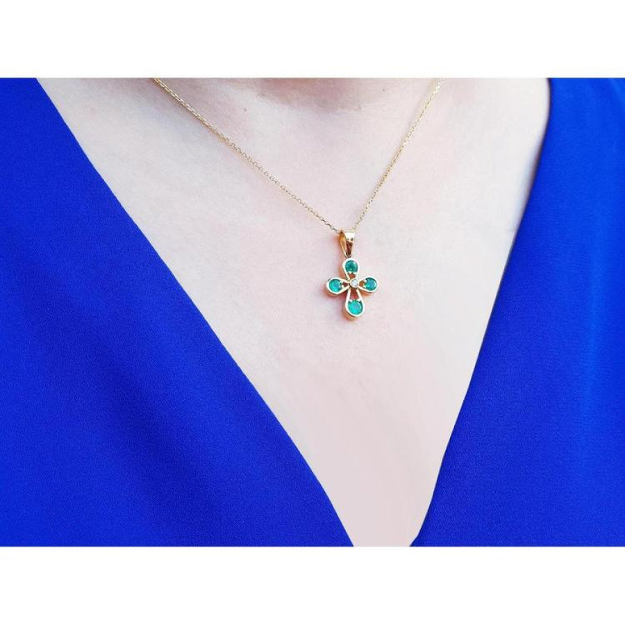 Emerald cross pendant with round-cut emeralds and a diamond accent, crafted in 18K yellow gold.