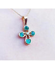 Emerald cross pendant with round-cut emeralds and a diamond in 18K yellow gold.