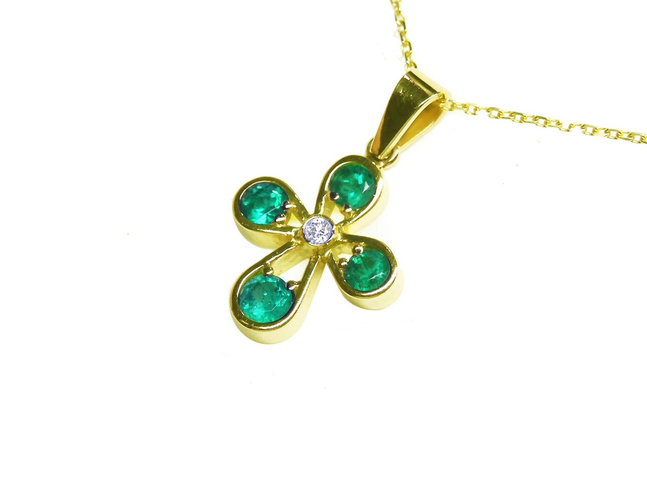 Gold necklace with a four-leaf cross pendant featuring natural colombian emeralds round cut each leaf.