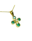 Gold necklace with a crossr-shaped pendant featuring natural emeralds from Colombia round cut.