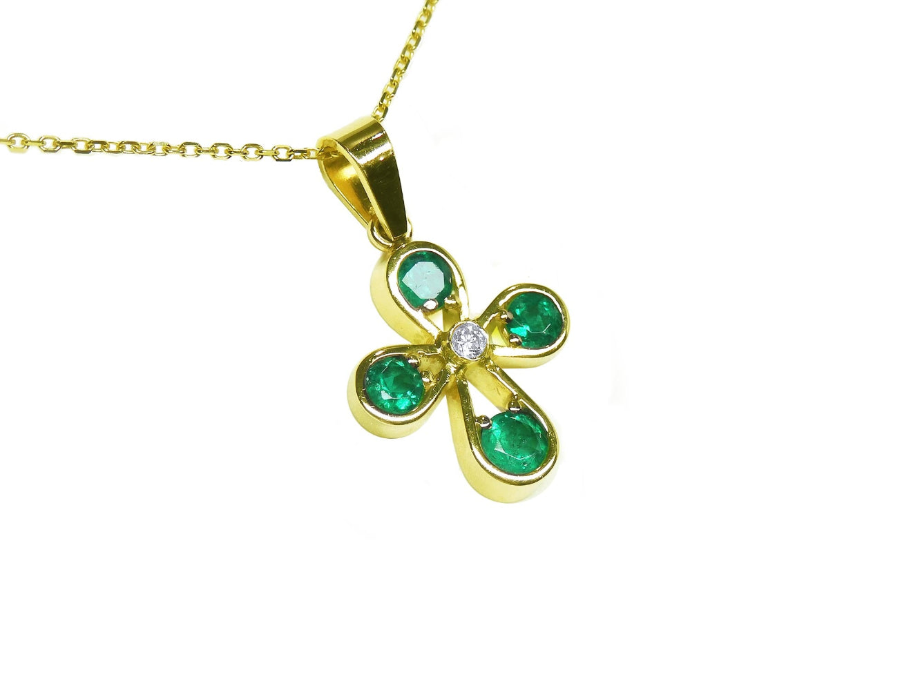 Gold necklace with a crossr-shaped pendant featuring natural emeralds on a right-side top position view.