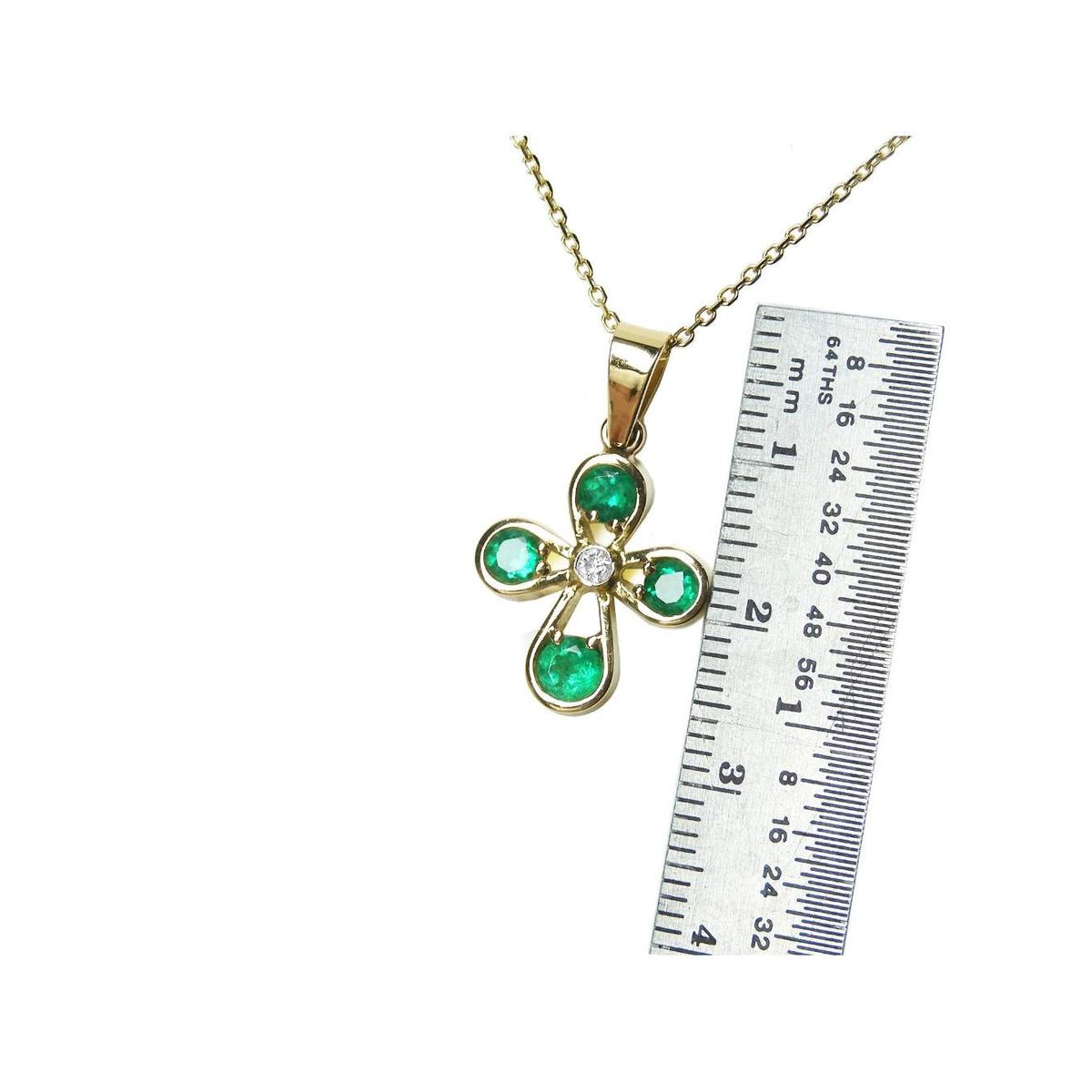 Gold necklace with an emerald cross pendant next to a ruler for scale on a white background.