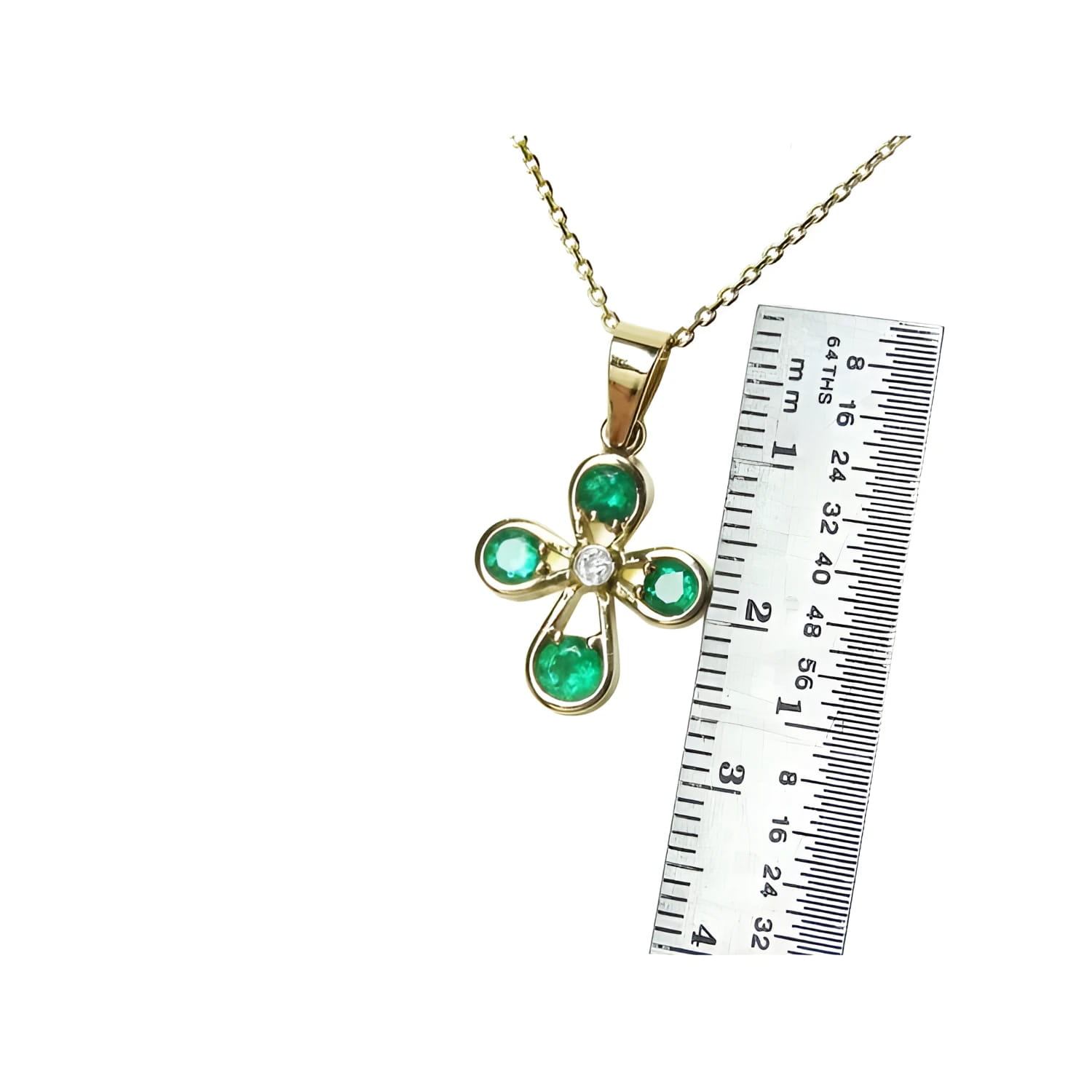 Yellow gold cross pendant with four round emeralds and a diamond center, shown with a ruler.