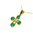 Yellow gold flower gold pendant with four round emeralds and a center diamond on a delicate chain.