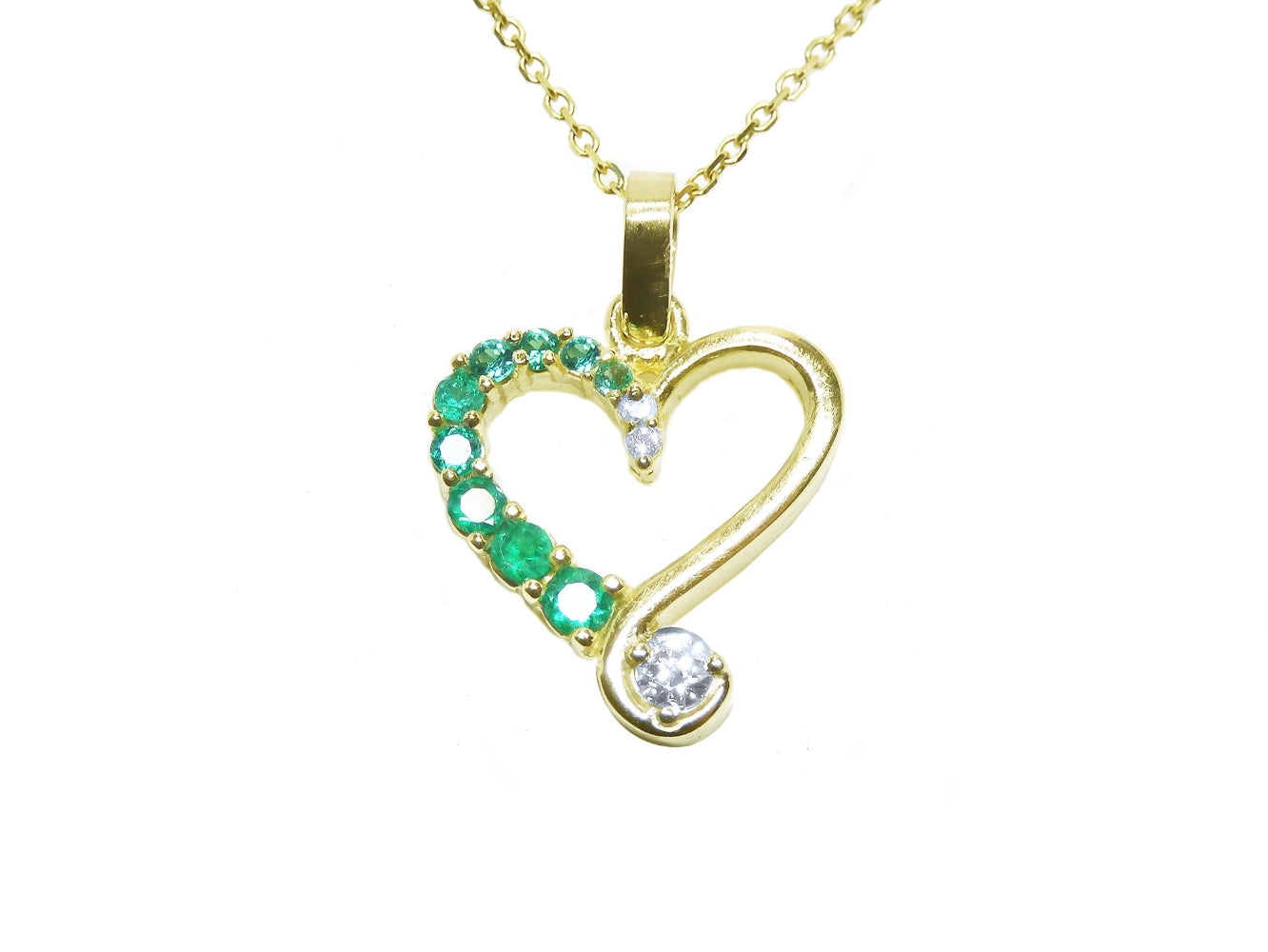 Gold heart-shaped pendant with natural round cut emeralds and diamond on a top profile view.