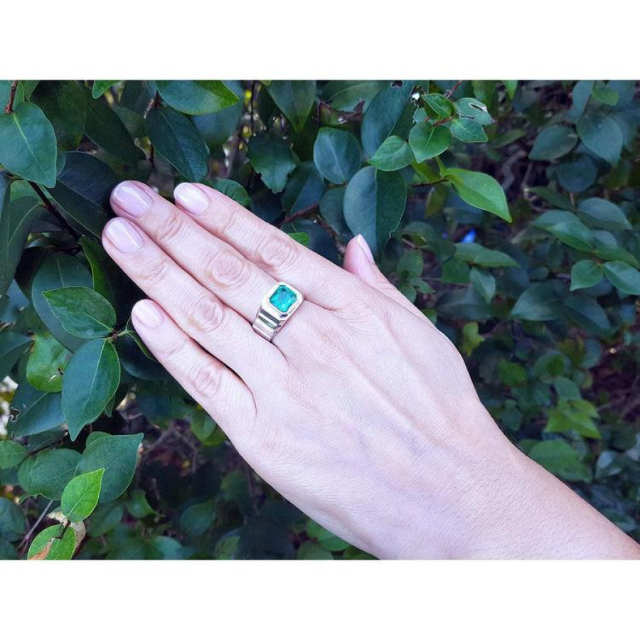 Men's 18K white gold ring with a bezel-set, deep bluish-green Muzo Colombian emerald.