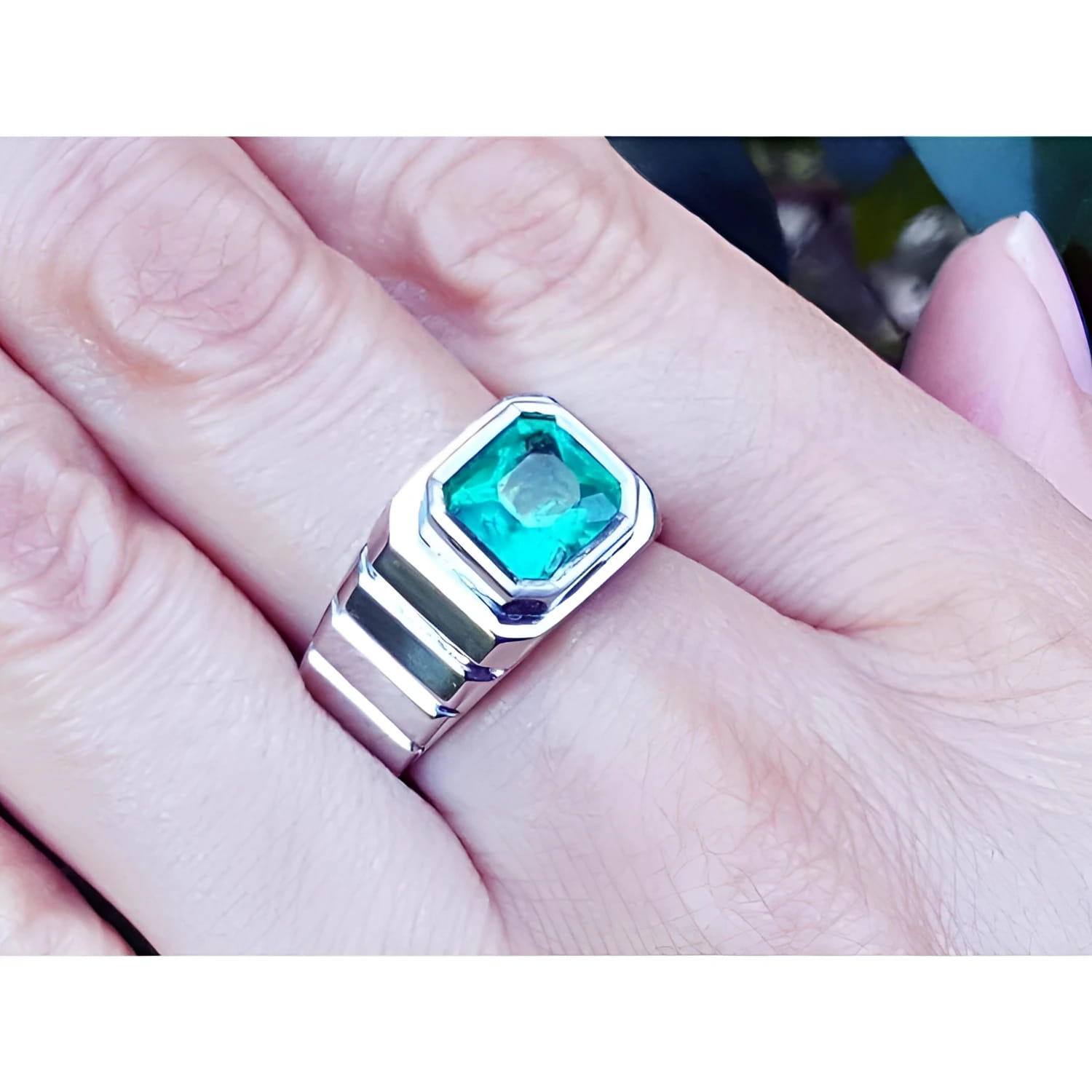 Men's 18K white gold ring with a bezel-set, deep bluish-green Muzo Colombian emerald.