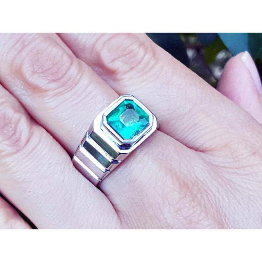 Men's 18K white gold ring with a bezel-set, deep bluish-green Muzo Colombian emerald.