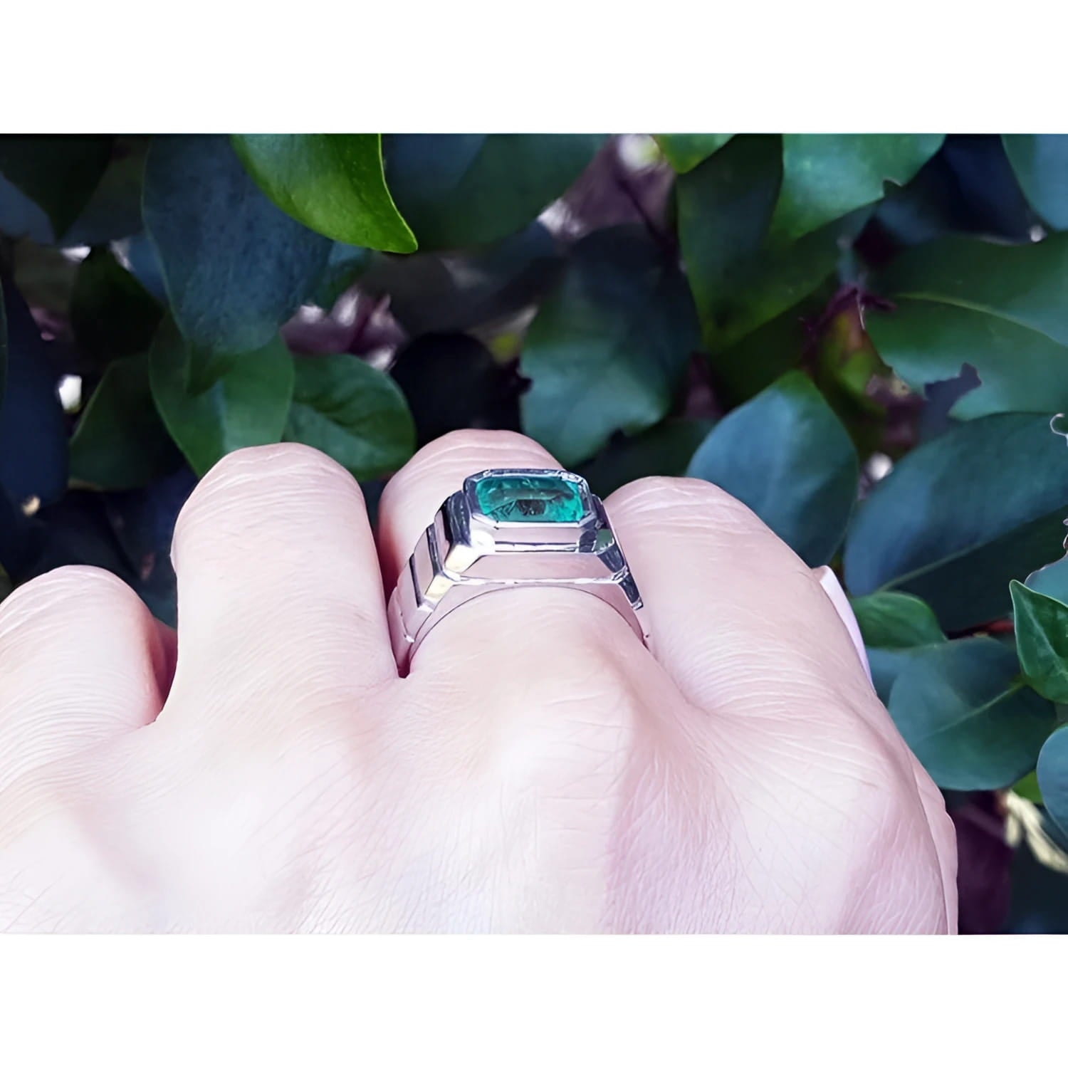 Men's 18K white gold ring with a bezel-set, deep bluish-green emerald.
