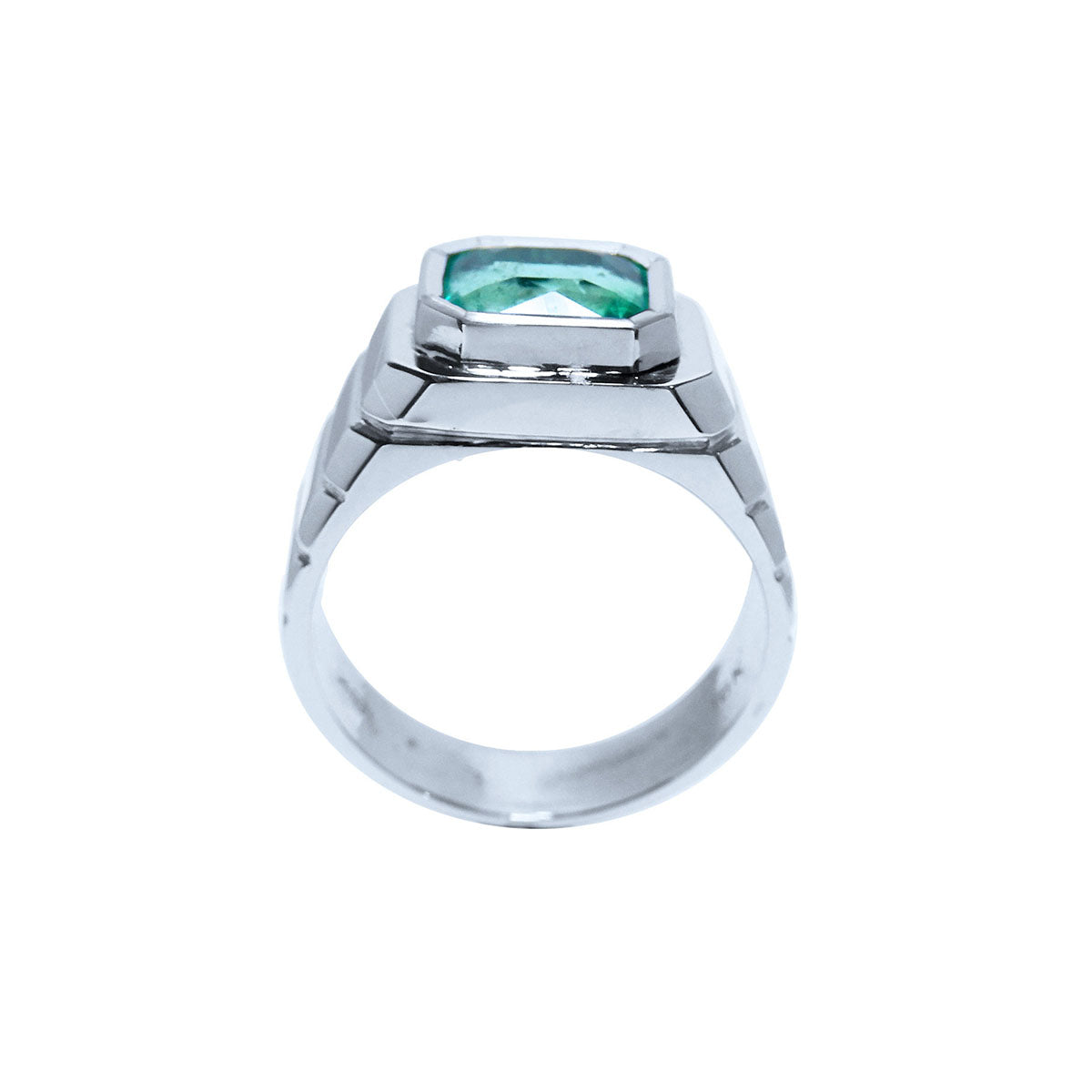 A lateral view of a white gold emerald solitaire ring for men showing the top bezel setting and band decoration.
