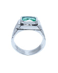A lateral view of a white gold emerald solitaire ring for men showing the top bezel setting and band decoration.