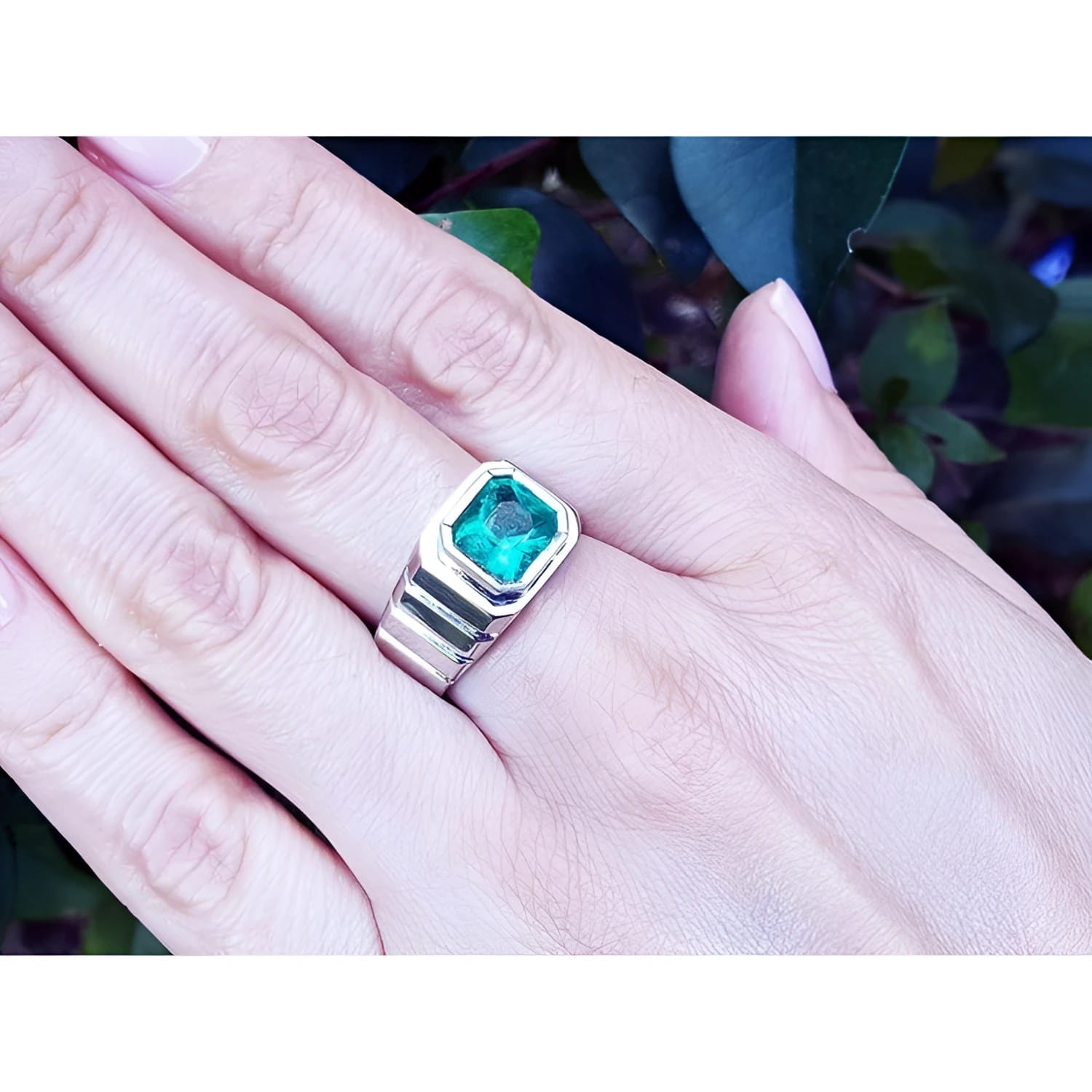 18K white gold men's ring with a deep bluish-green, bezel-set, modified emerald-cut Muzo Colombian emerald.