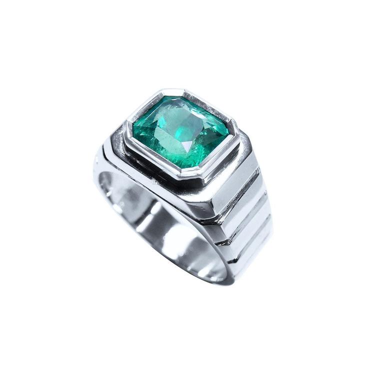 This mens solitaire ring in white gold shows the top bezel set colombian emerald and partial perspective sides decoration.