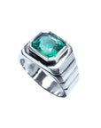 This mens solitaire ring in white gold shows the top bezel set colombian emerald and partial perspective sides decoration.