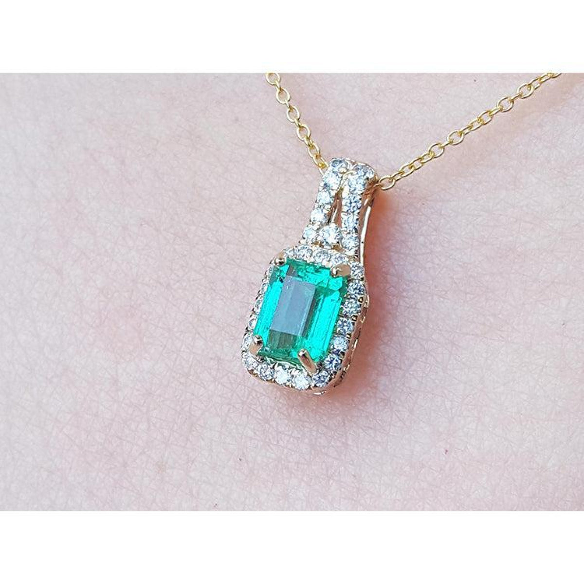 Emerald cut Colombian emerald slider pendant with halo diamonds on a 14K gold chain.