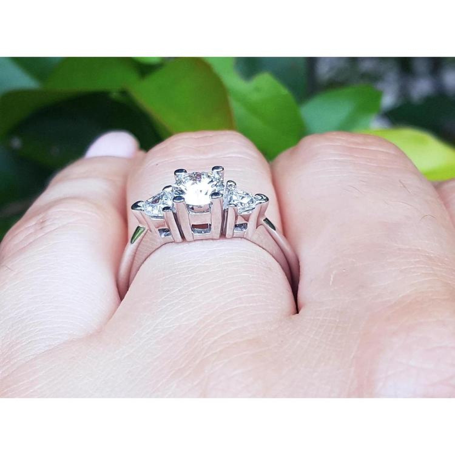 14K white gold engagement ring with a round center diamond and two trillion side diamonds.